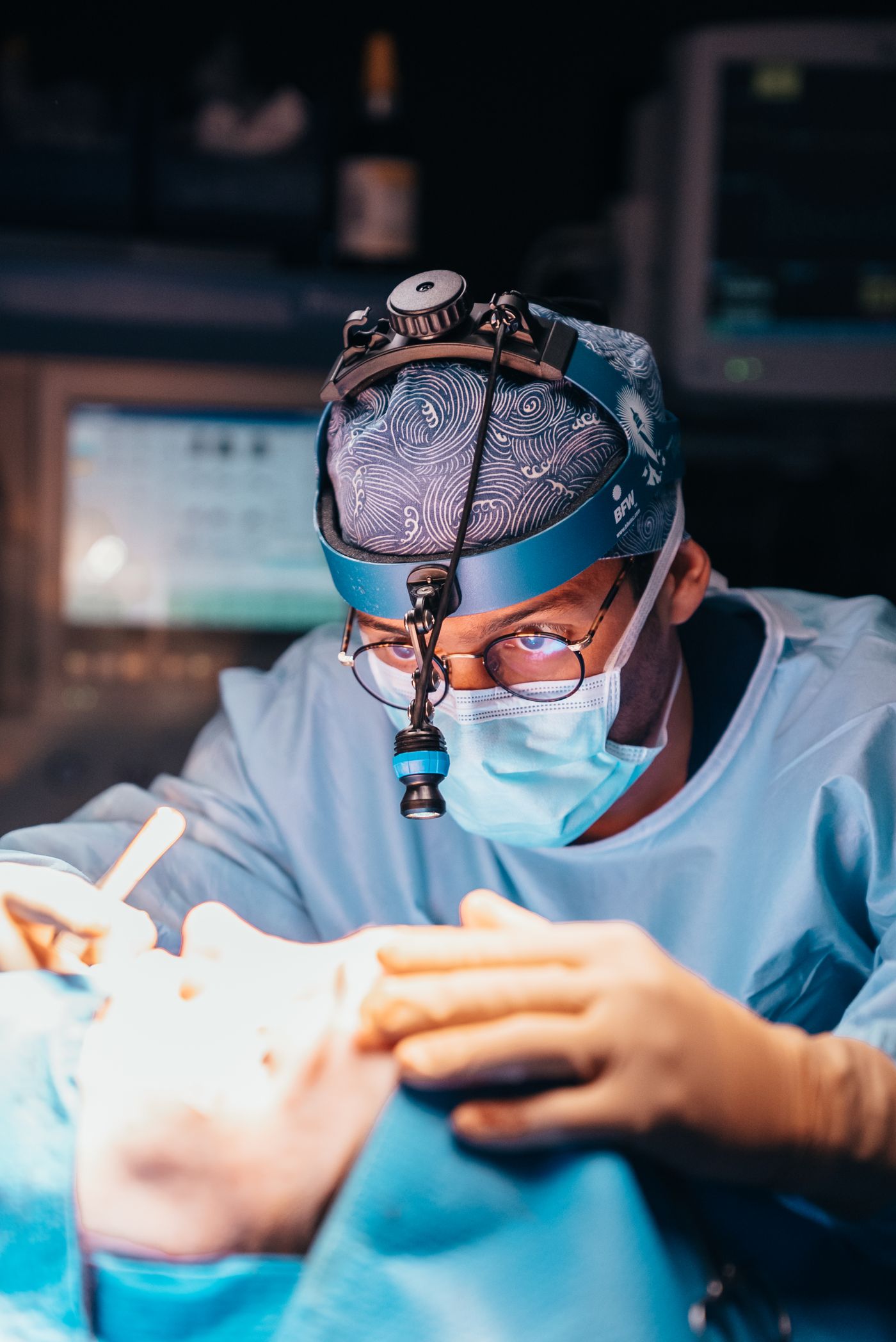 Le Dr Pierre Gagnieur concentré pendant une rhinoplastie, sous lumière frontale